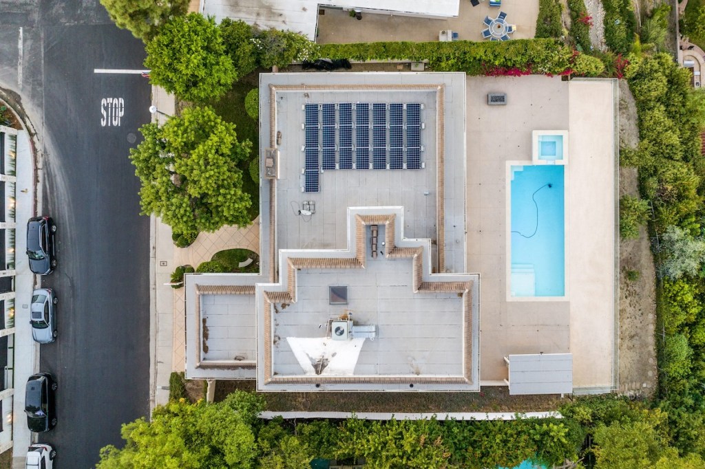 An aerial view of a smart modern villa with a pool heated by Thermomine.io smart crypto mining solutions and using roof smart solar system for double benefit.