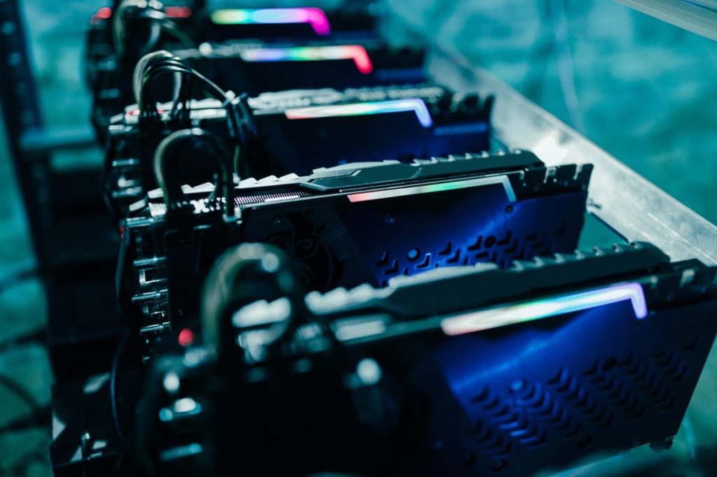 A close-up shot captures several computer servers with sleek, dark exteriors lined up, displaying integrated lighting that casts a futuristic ambiance. The image features a striking contrast, highlighting the cool, modern design of the hardware components.